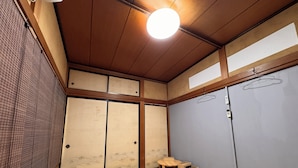A traditional Japanese room with tatami flooring, sliding doors, and a hanging light fixture. - Calmbase Nishiizu Izayoi (Numazu)