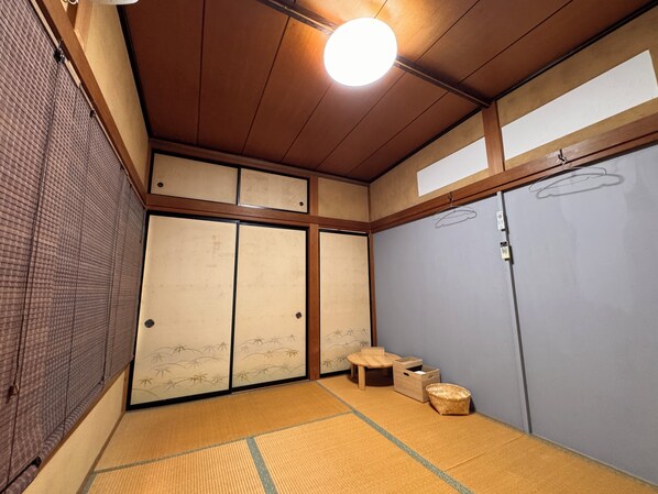 A traditional Japanese room with tatami flooring, sliding doors, and a hanging light fixture.