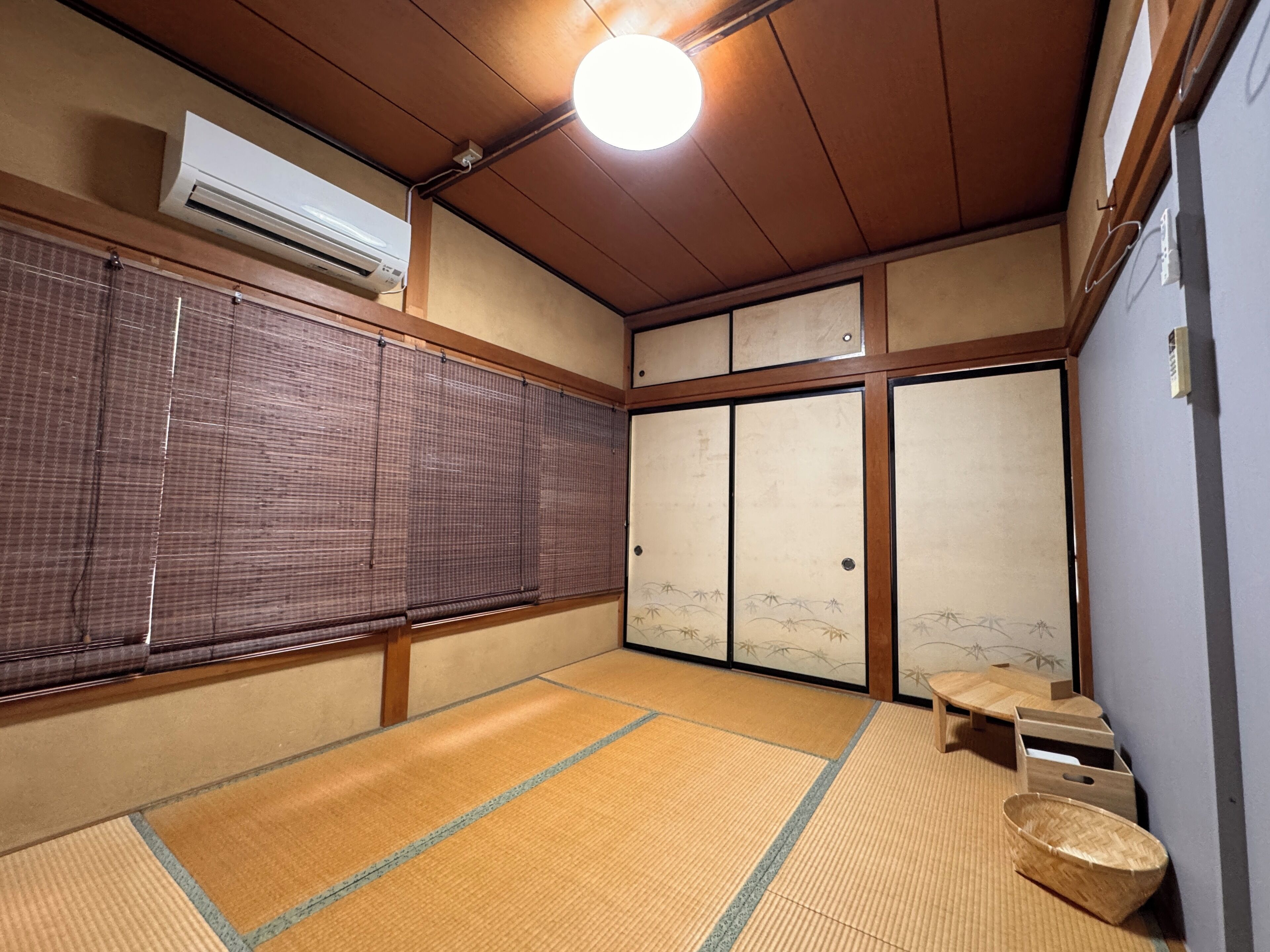 Una habitación japonesa tradicional con suelo de tatami, puertas correderas y un ventilador de techo.