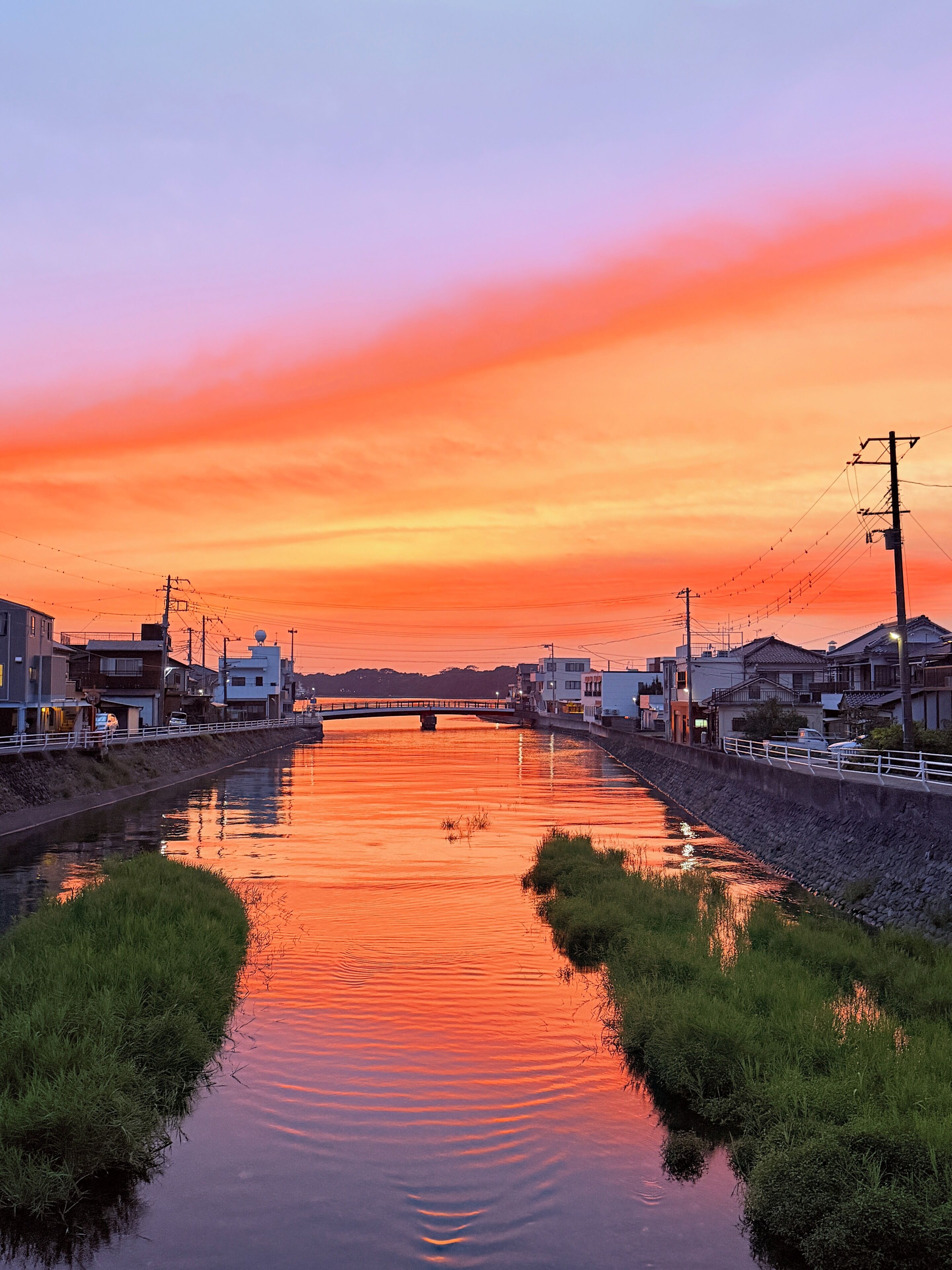 A calm river at sunset with buildings on either side.