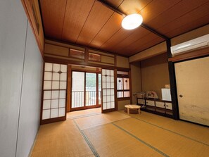 Una habitación japonesa tradicional con suelo de tatami, puertas correderas y un ventilador de techo.