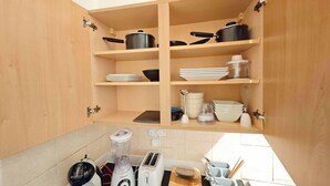 A kitchen with wooden cabinets, a countertop with a blender, toaster, and a coffee maker. - Pinewood Cozy Apartment in Dundee (Dundee)