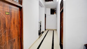 A narrow hallway with wooden doors, a tiled floor, and a staircase leading to an upper level. - Hotel O Prayagraj Sangam Railway (Prayagraj)