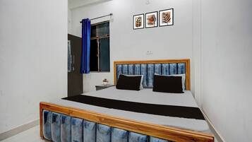 Ein Schlafzimmer mit Bett, Nachttisch, einem Fenster mit Vorhängen und Wandbildern.