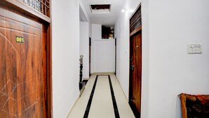 A corridor with wooden doors, a tiled floor, and a ceiling light. - Hotel O Prayagraj Sangam Railway (Prayagraj)