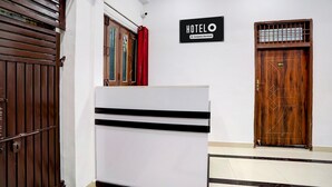 A hotel lobby with a reception desk, a wooden door, and a sign indicating the hotel is company-serviced. - Hotel O Prayagraj Sangam Railway (Prayagraj)