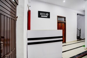 Entrada de un hotel con un cartel que indica servicio de empresa, una puerta de madera y una escalera que conduce al interior.