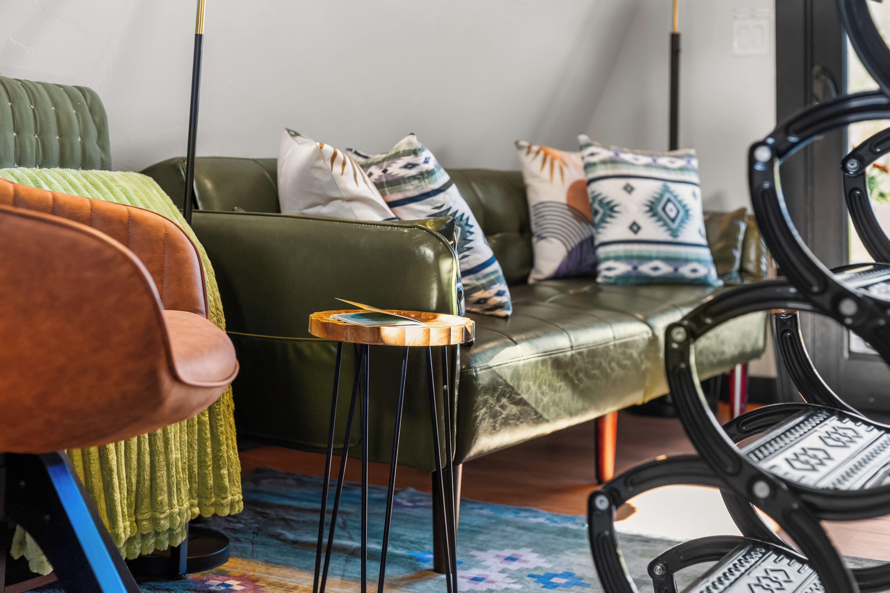 A modern living room with a green sofa, a wooden side table, and a black chair.