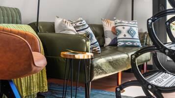 A modern living room with a green sofa, a wooden side table, and a black chair.