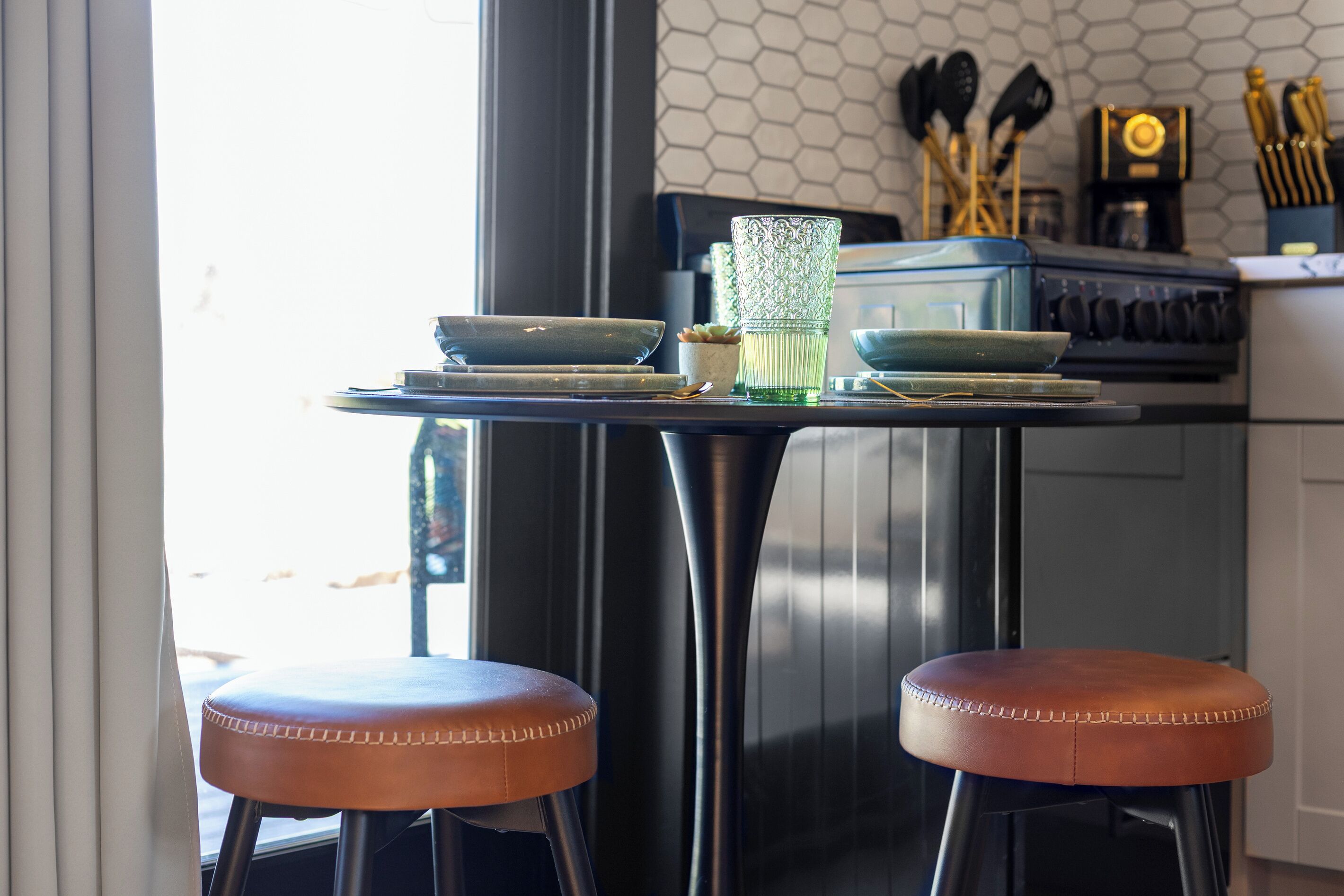 A kitchen with a dining table, stools, and a stove.