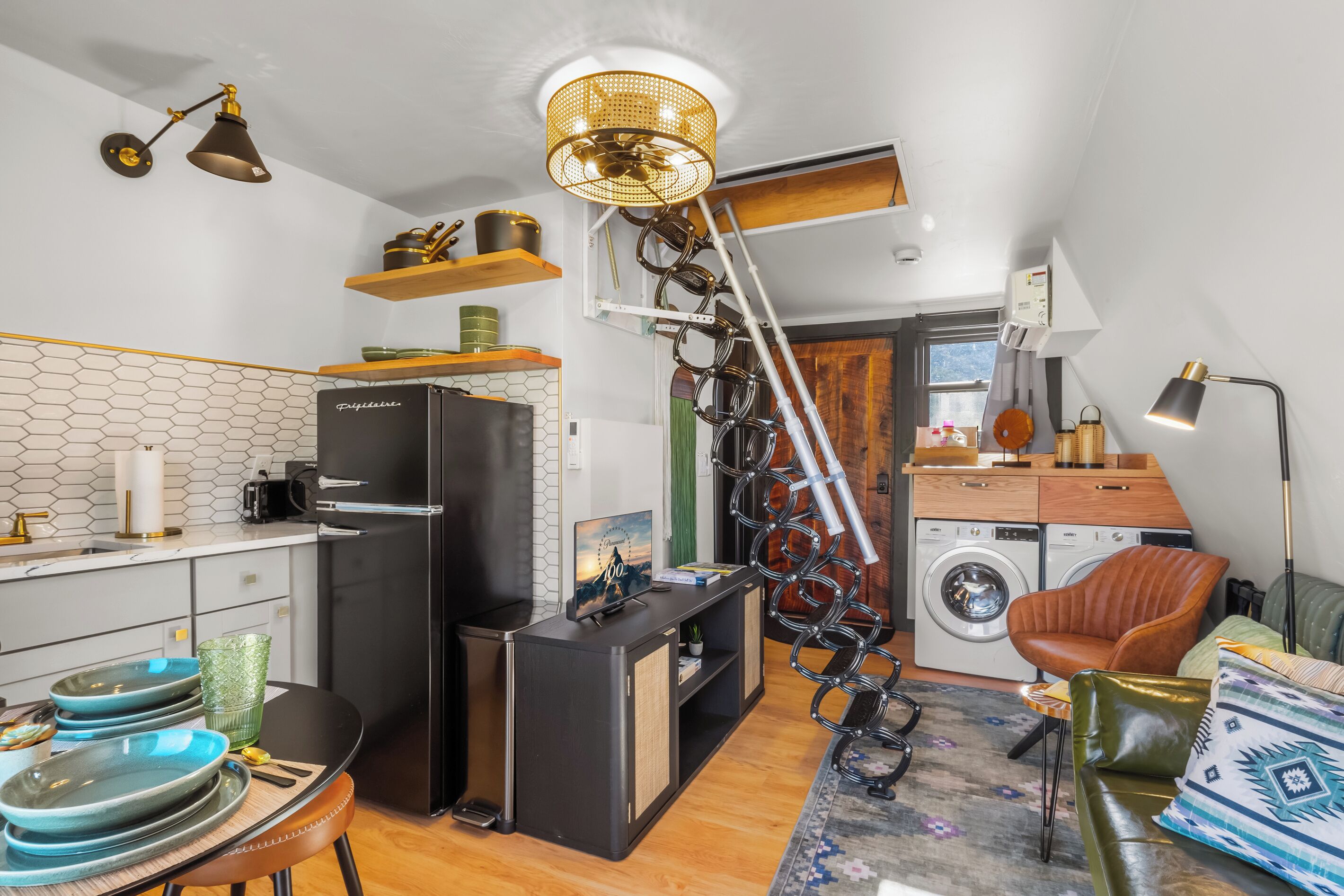 A compact kitchen with a refrigerator, a washing machine, and a dining area with a table and chairs.