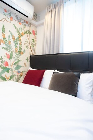 A bed with a black headboard, white bedding, and three pillows in red, gray, and white. - 1 min walk from sta./Excellent access to central (Osaka)