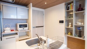 Een moderne keuken met witte kastjes, een magnetron, een waterkoker en een ingebouwde televisie.