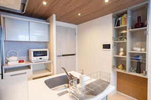 A modern kitchen with white cabinetry, a microwave, a kettle, and a built-in TV. - 1 min walk from sta./Excellent access to central (Osaka)