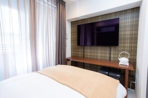 A hotel room with a bed, a TV mounted on the wall, a bedside table with a kettle, and a window with curtains. - 1 min walk from sta./Excellent access to central (Osaka)
