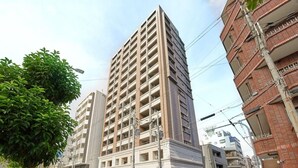 Un edificio de varios pisos con fachada plana, rodeado de otros edificios y una calle.