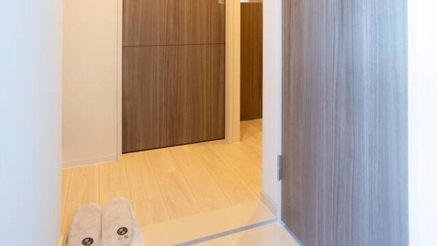 Un couloir avec une porte en bois et un sol carrelé.