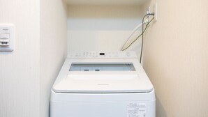 Un lave-linge à chargement frontal doté d’un panneau de commande, d’une prise de courant et d’un porte-serviettes situé au-dessus.