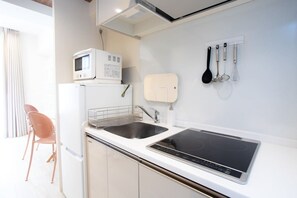 A compact kitchen with a microwave, sink, and stove, a chair, and a window with curtains. - 1 min walk from sta./Excellent access to central (Osaka)
