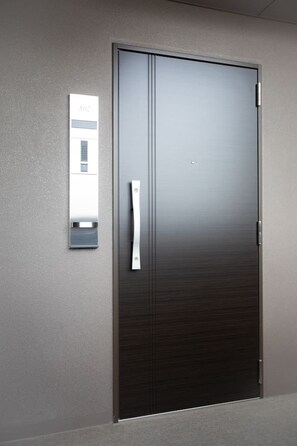 A dark-colored door with a metallic handle and a small rectangular mirror mounted on the wall to its left. - 1 min walk from sta./Excellent access to central (Osaka)