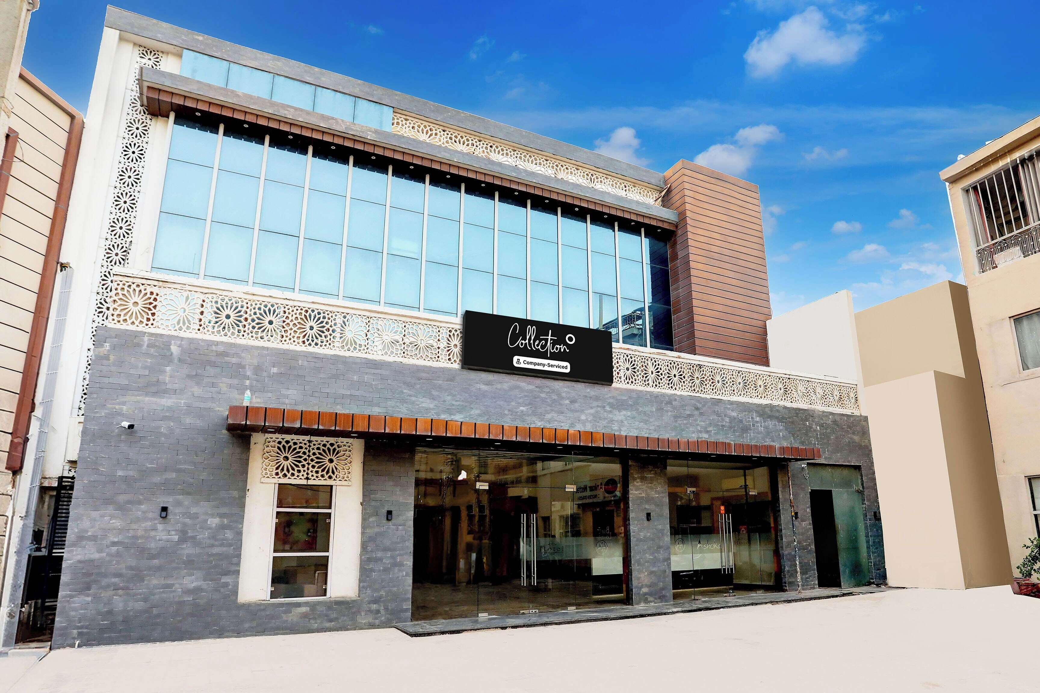 A hotel with a modern facade, large windows, and a sign indicating it is a company-serviced collection.