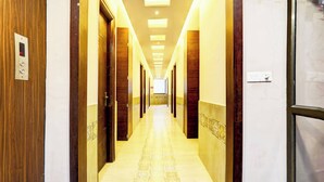 Un pasillo de hotel con varias puertas, techo iluminado y suelo estampado.
