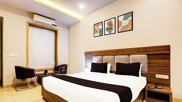 Habitación de hotel con una cama grande, un escritorio con silla, un teléfono y aire acondicionado de pared.