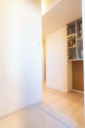 A hallway with a wooden floor, a white wall, and a glass-fronted cabinet with various items. - 1 min walk from sta./Excellent access to central (Osaka)