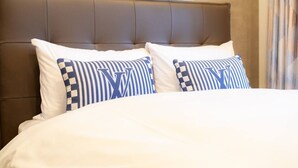 A bed with white bedding and two pillows with a checkered pattern and a large letter 'W'. - 1 min walk from sta./Excellent access to central (Osaka)