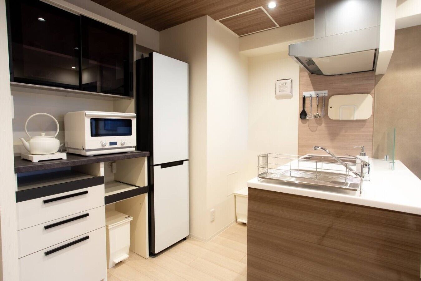 A modern kitchen with a microwave, kettle, and refrigerator.