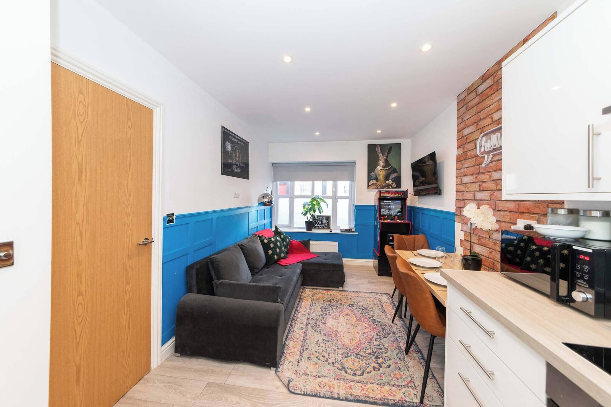 A compact living space with a kitchenette, a dining area, and a seating area with a sofa and a rug.