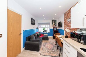 Ein kompakter Wohnraum mit Küchenzeile, Essbereich und einer Sitzecke mit Sofa und Teppich.