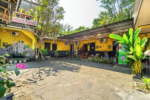 A courtyard with a stone floor, yellow walls, and various plants. - Udan Mas Borobudur By ARBA (Borobudur)