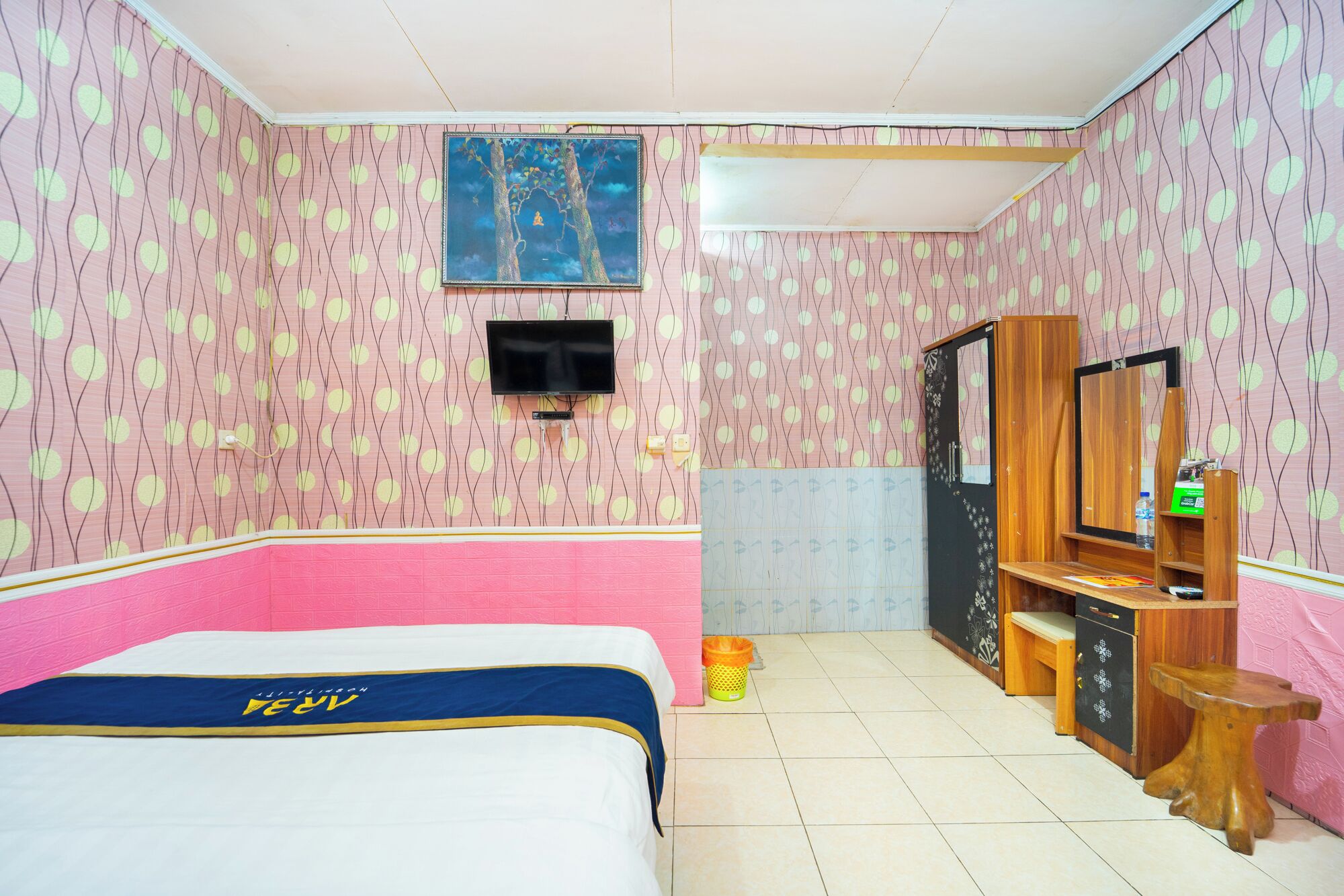 Une chambre avec un lit, un téléviseur fixé au mur, une armoire en bois et un miroir.