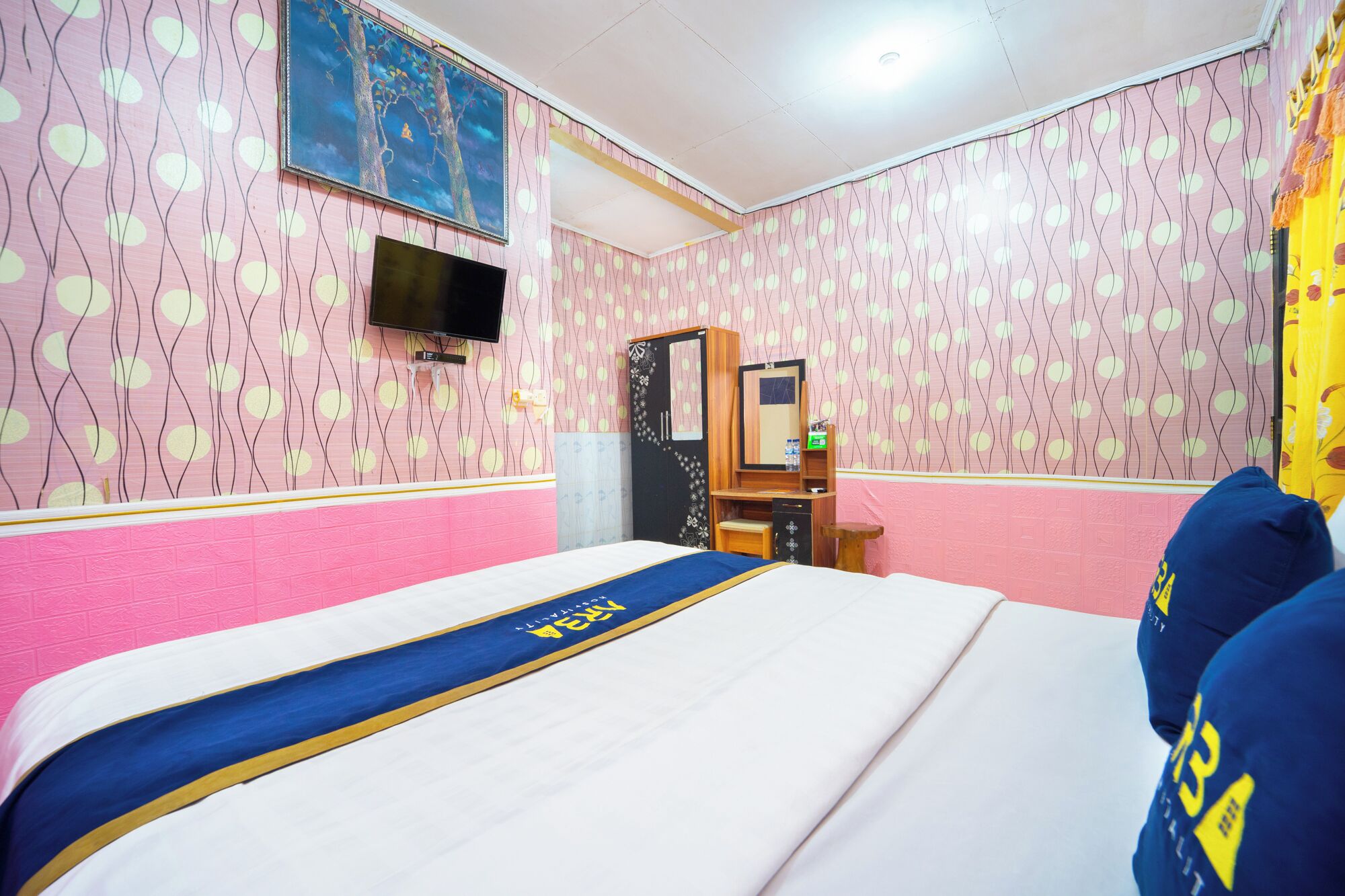 Habitación de hotel con cama, escritorio, armario, televisión y papel tapiz estampado.