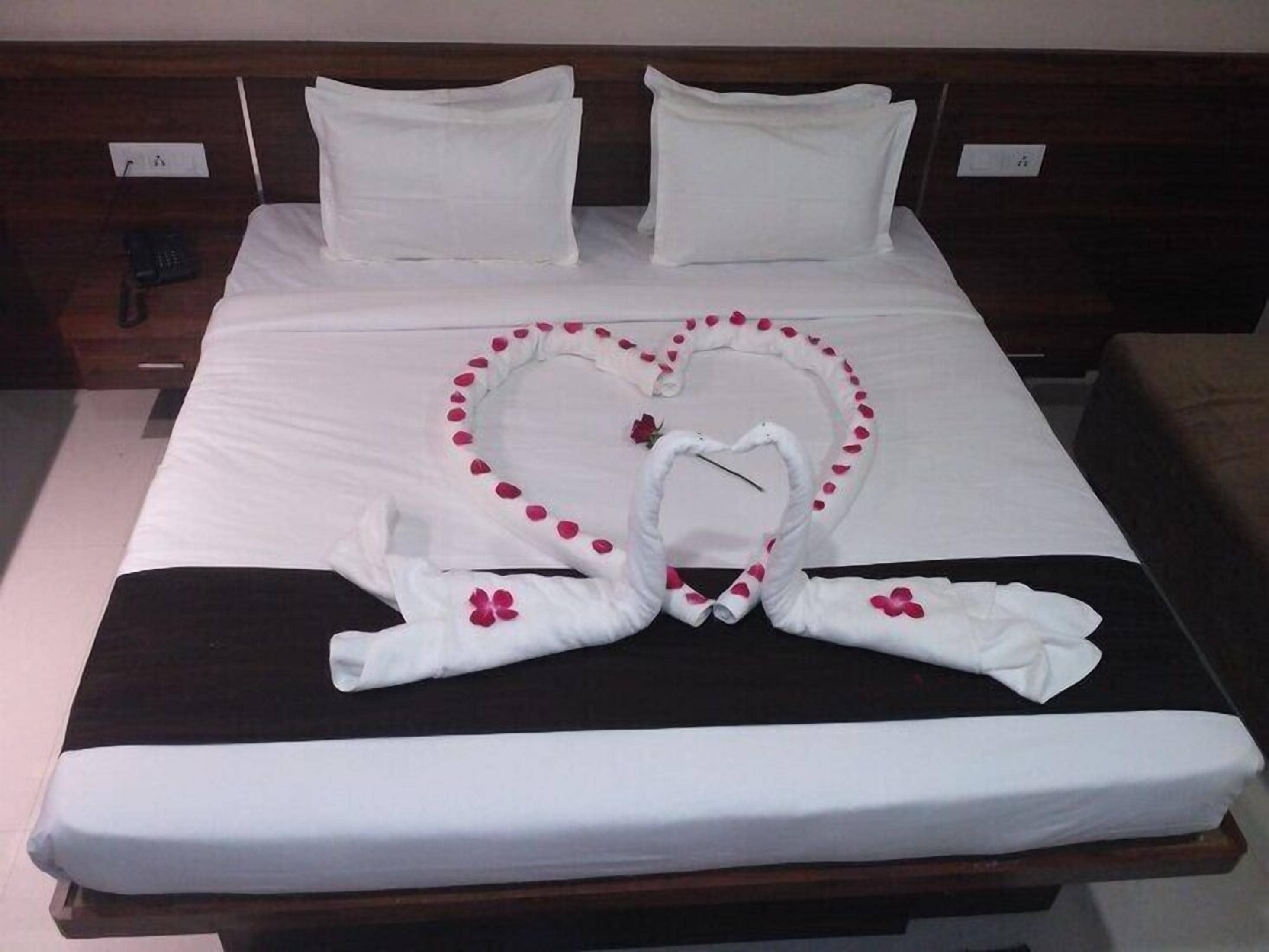 Een hotelkamer met een bed, kussens en een handdoekarrangement in de vorm van een hart.