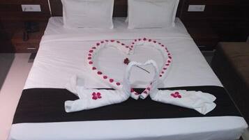 A hotel room with a bed, pillows, and a heart-shaped towel arrangement.