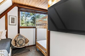 A bedroom with a bed, a chair, and a large window. - A-Frame | Hot Tub Deck | Fireplace | Trails, Golf & Marina | A Big Bear View (Big Bear Lake)