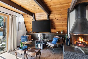 Ein gemütliches Wohnzimmer mit Kamin, Holzwänden, einem Flachbildfernseher und bequemen Sitzgelegenheiten.