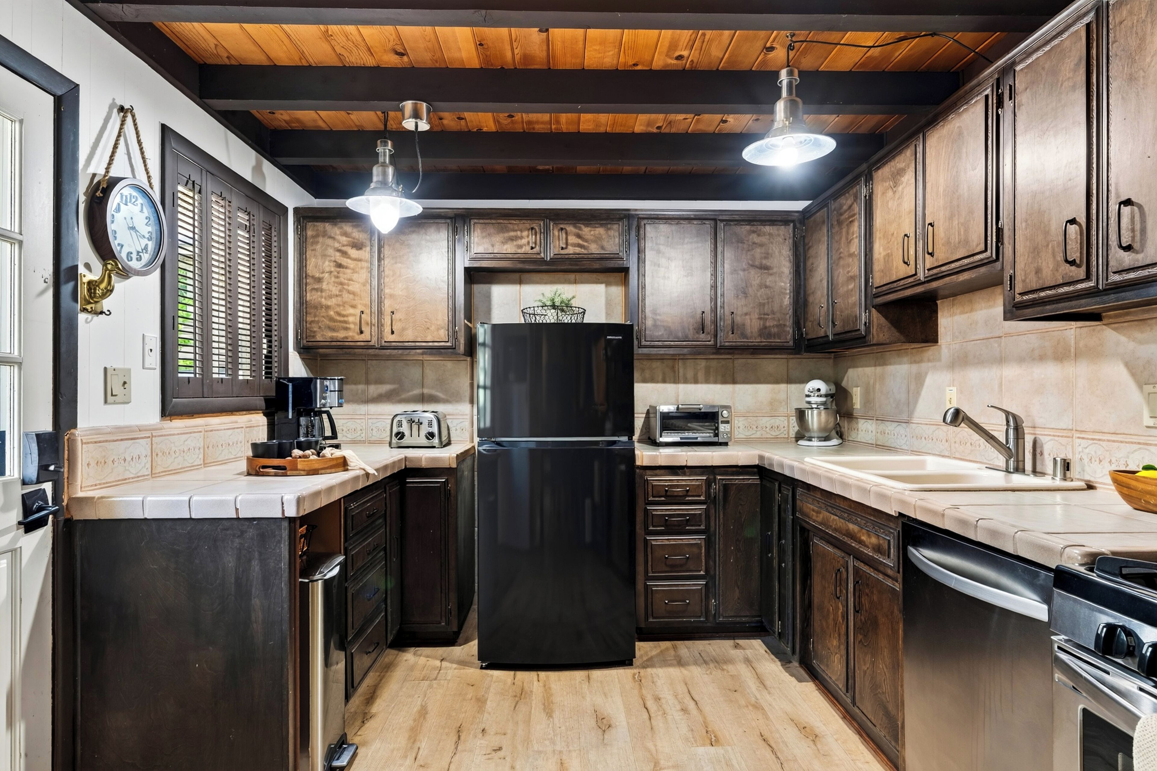 A kitchen with wooden cabinets, a black refrigerator, a toaster, and a sink.