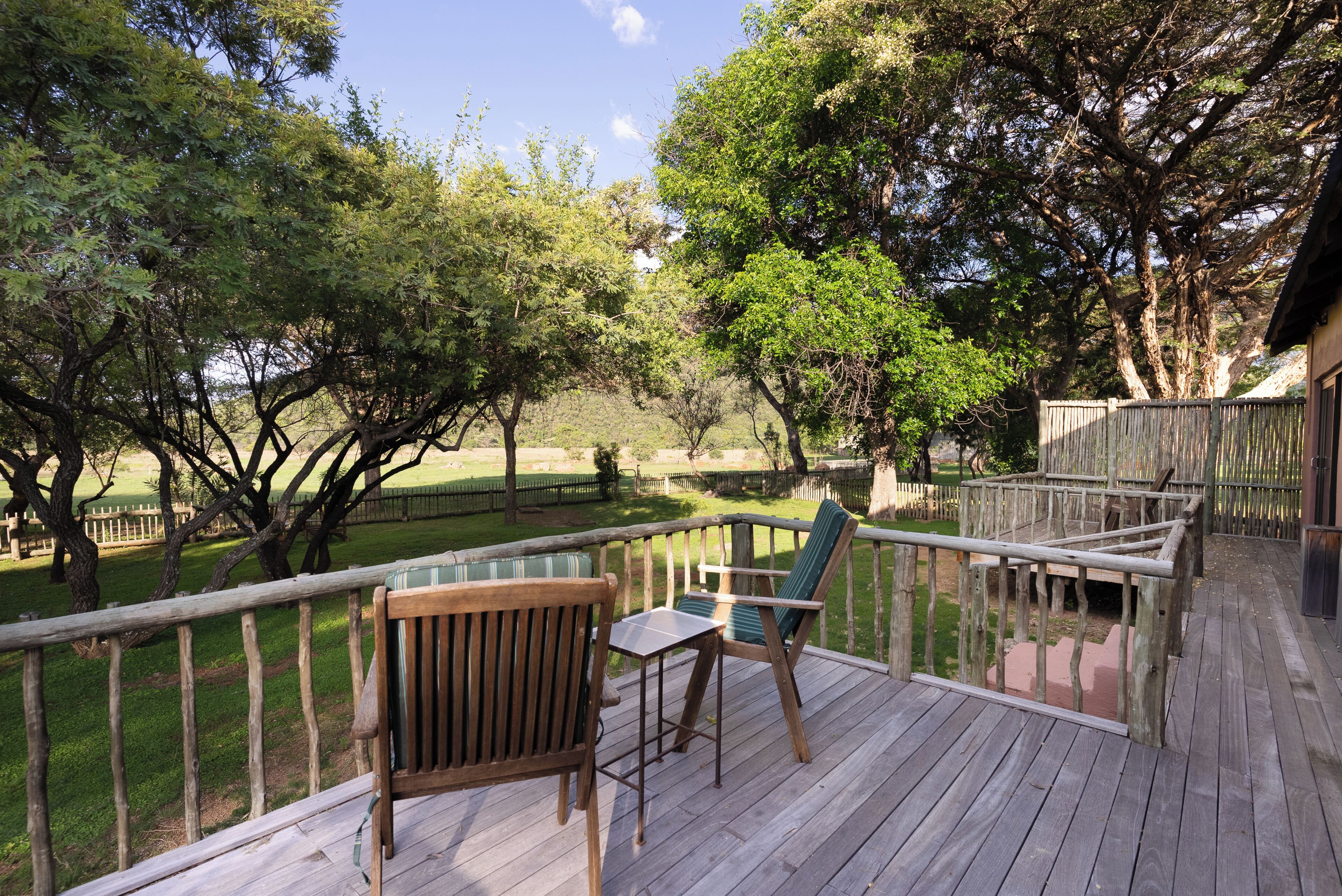 A wooden deck with a view of a grassy area and trees.