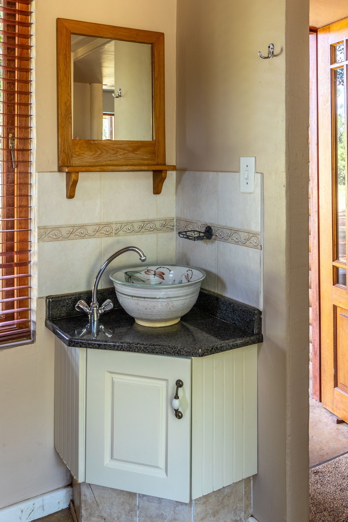 A bathroom with a white cabinet, a glass bowl sink, a wooden-framed mirror, and a towel rack.