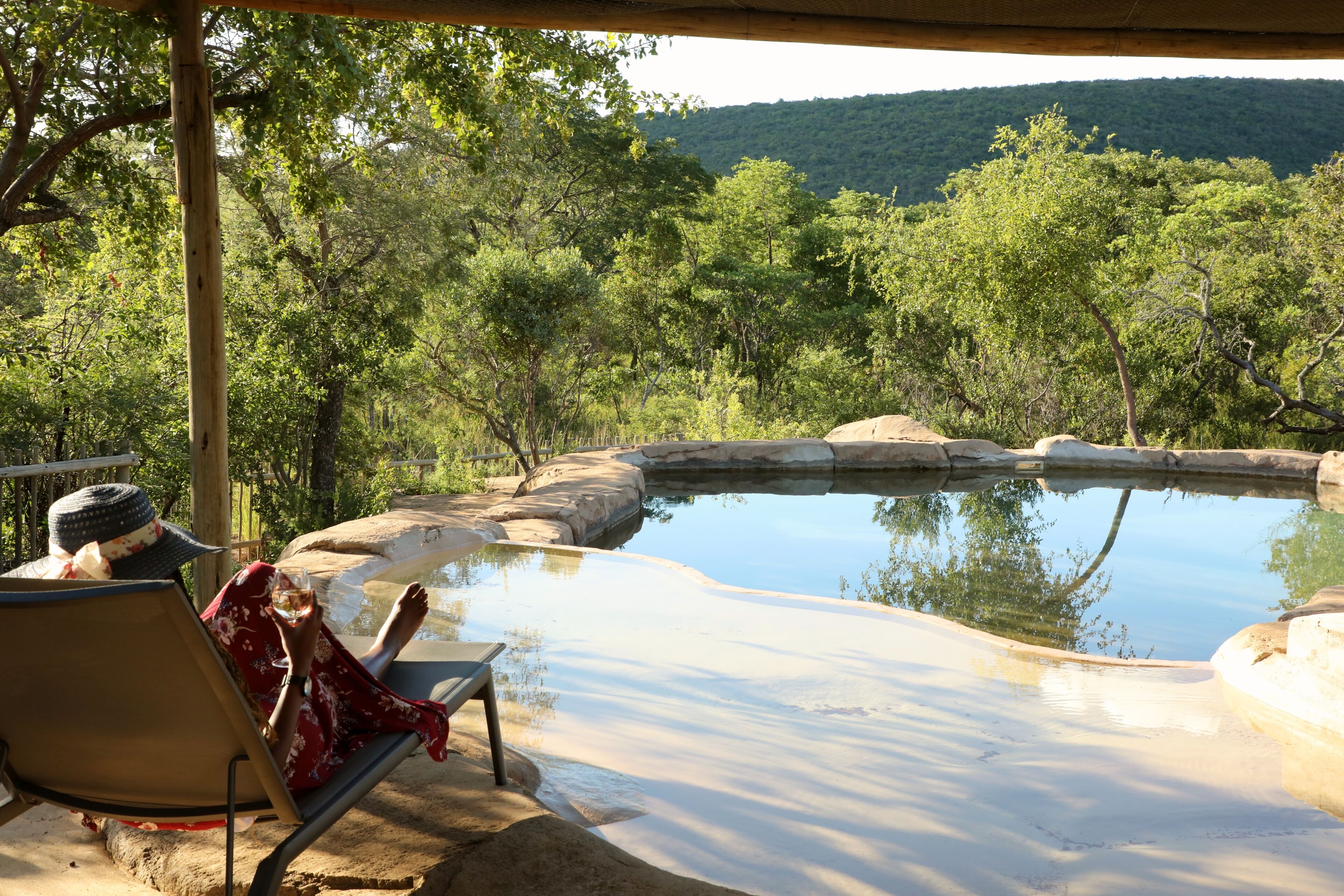 A pool area with a view of a forested hillside.