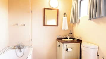 Ein Badezimmer mit einer Badewanne, einer Toilette, einem Waschbecken und einem Spiegel.