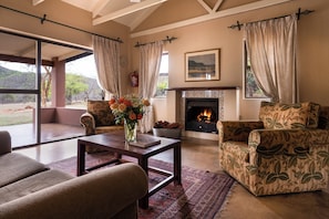 Un salón espacioso con chimenea, asientos cómodos y un ventanal con vistas al exterior.