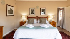 Habitación de hotel con una cama grande, dos mesitas de noche con lámparas, un cabecero de madera y cuadros enmarcados en la pared.