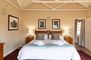 Habitación de hotel con una cama grande, dos mesitas de noche con lámparas, un cabecero de madera y cuadros enmarcados en la pared.