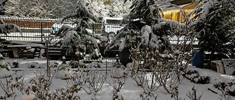 A snow-covered outdoor area with a bus and a building with lights.
