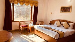 A hotel room with a bed, a desk, a chair, and a window with curtains.