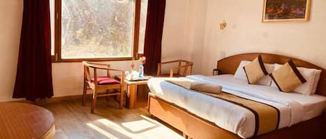 Ein Hotelzimmer mit einem Bett, einem Schreibtisch, einem Stuhl und einem fensterbepflanzten Fenster.